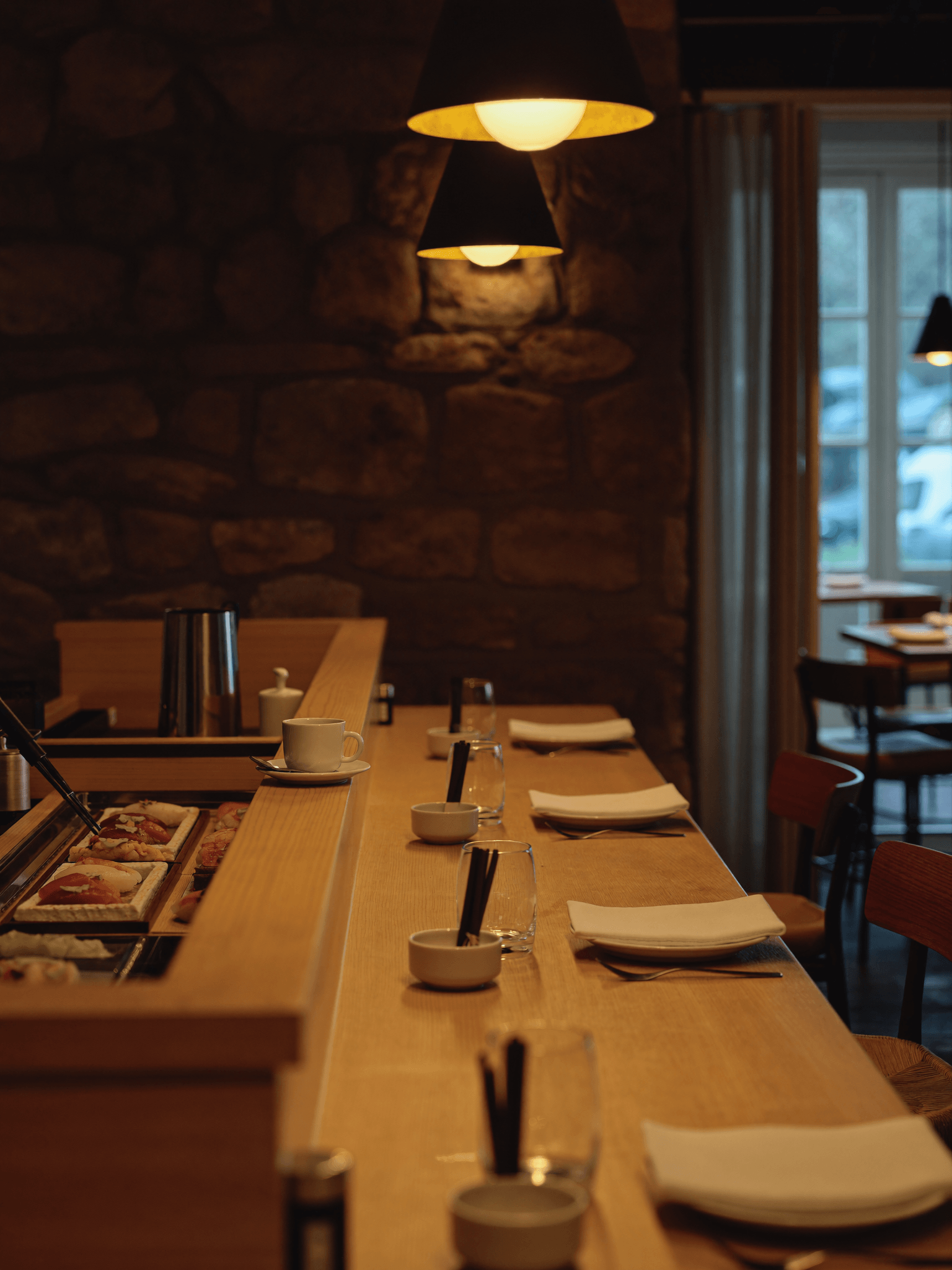 Comptoir à sushis en bois clair dans une salle intimiste